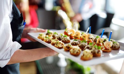 Waiter carrying plates with meat dish on some festive event, party or wedding reception